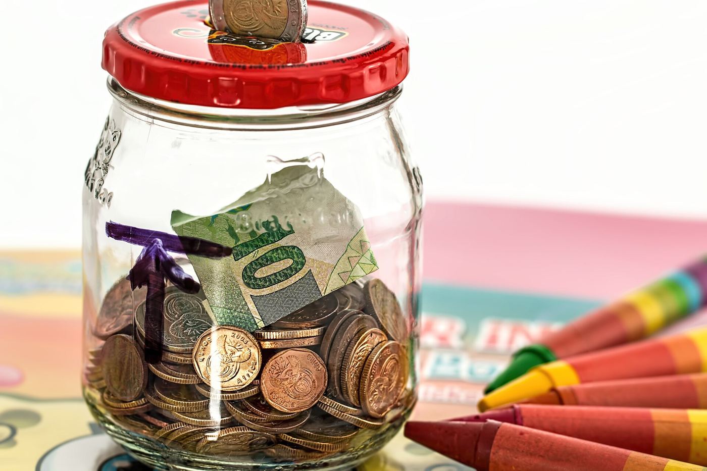 A piggy bank surrounded by coins representing personal savings and careful household budgeting.